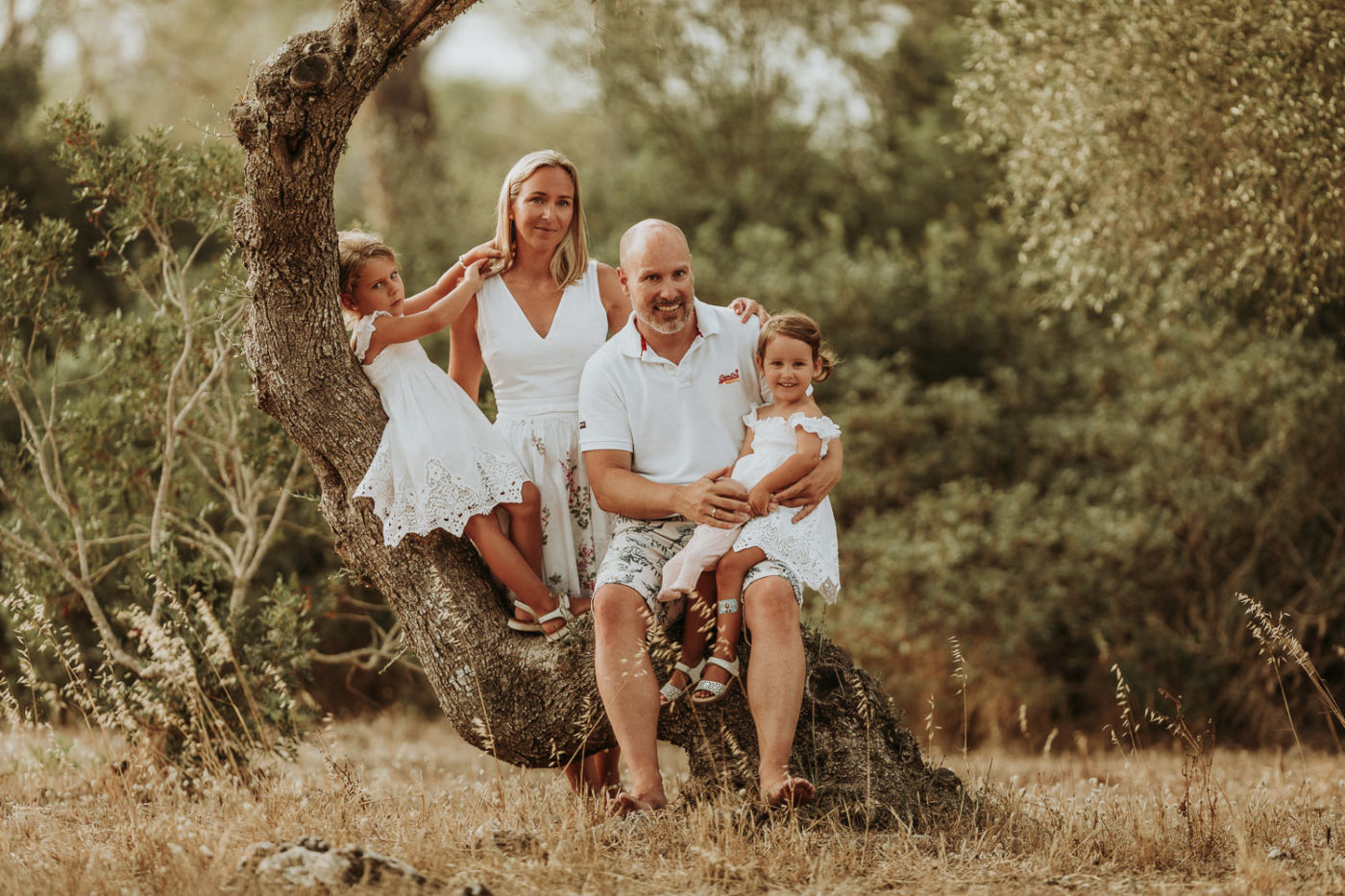 Farbiges Familiengruppenfoto zwischen wilden Olivenbäumen.